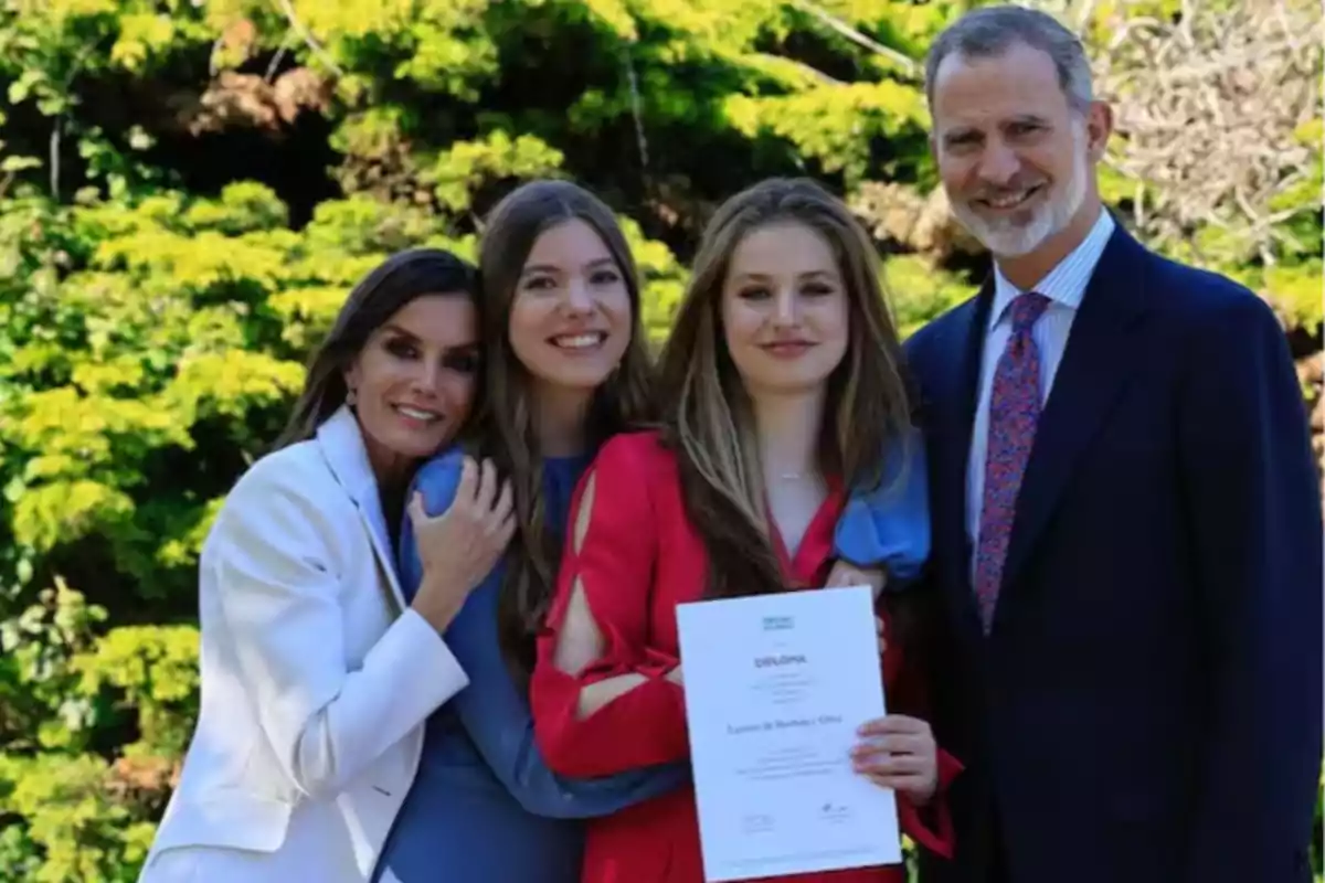 Una familia sonriente posa al aire libre mientras una de las personas sostiene un diploma.