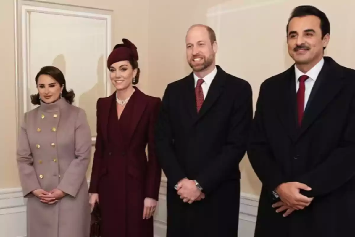 Cuatro personas posan juntas en una habitación, dos mujeres y dos hombres, todos vestidos formalmente.