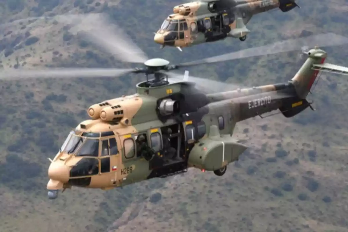 Dos helicópteros militares en vuelo sobre un paisaje montañoso.