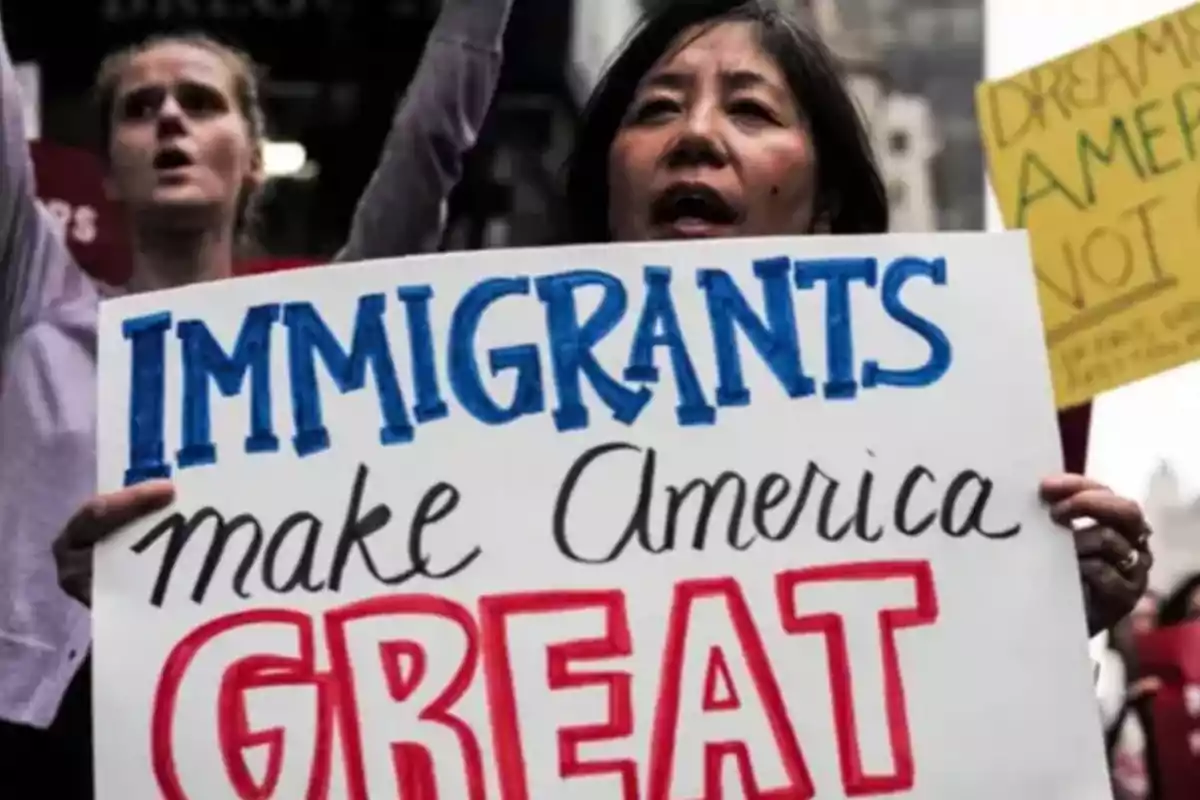 Persona sosteniendo un cartel que dice "Immigrants make America great" en una manifestación.