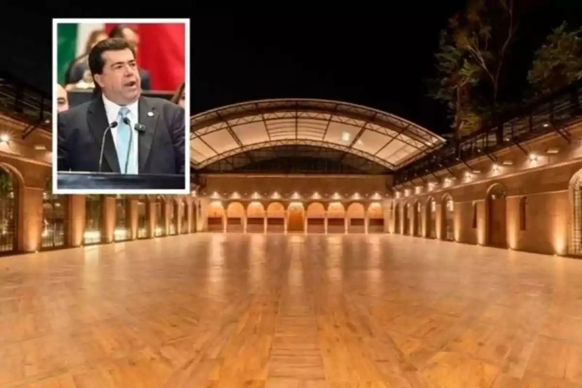 A man speaking at a podium with a background of a large, well-lit room with a glass ceiling and arches.