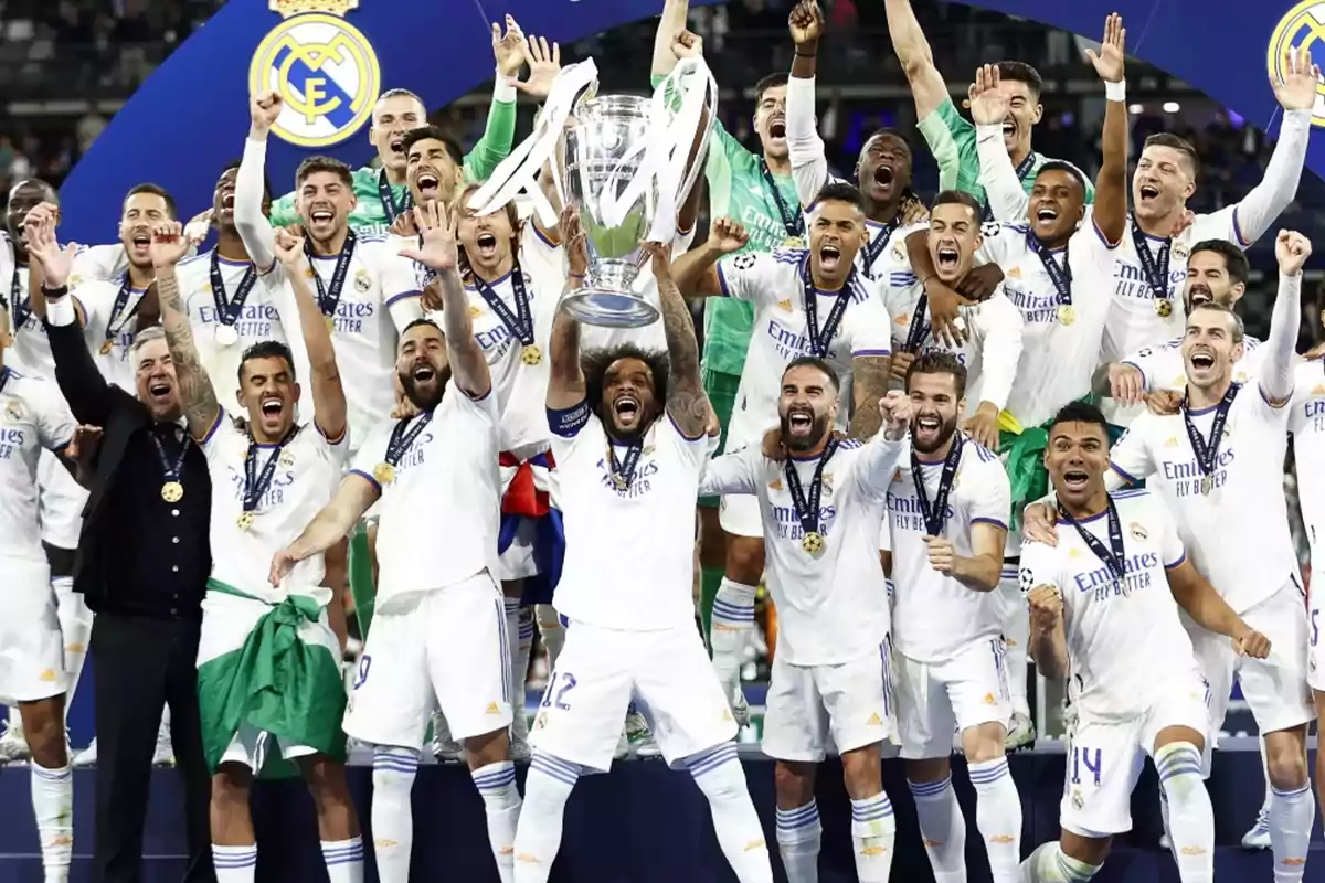 Jugadores de un equipo de fútbol celebran con un trofeo, levantándolo en el aire mientras sonríen y gritan de alegría.