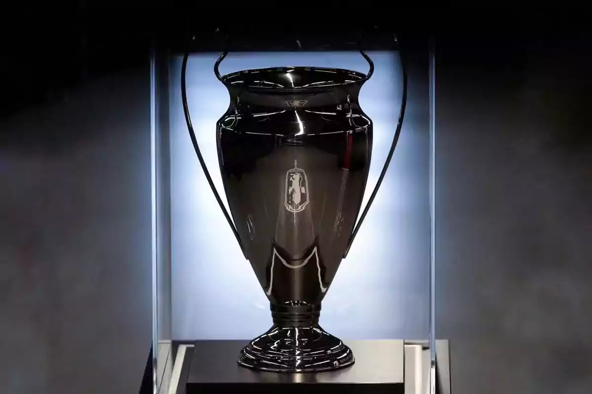 Trofeo de fútbol en una vitrina iluminada con fondo oscuro.