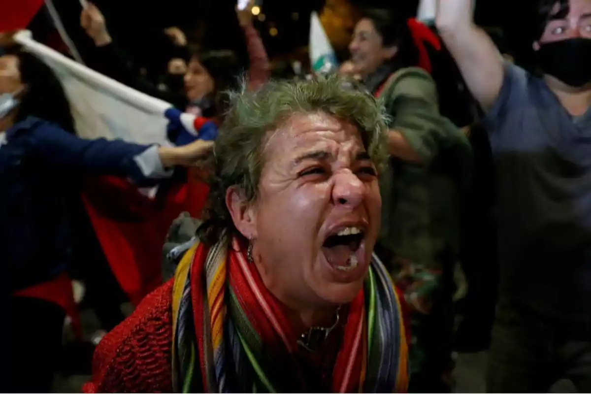 Una persona gritando con emoción en una multitud durante una manifestación nocturna.