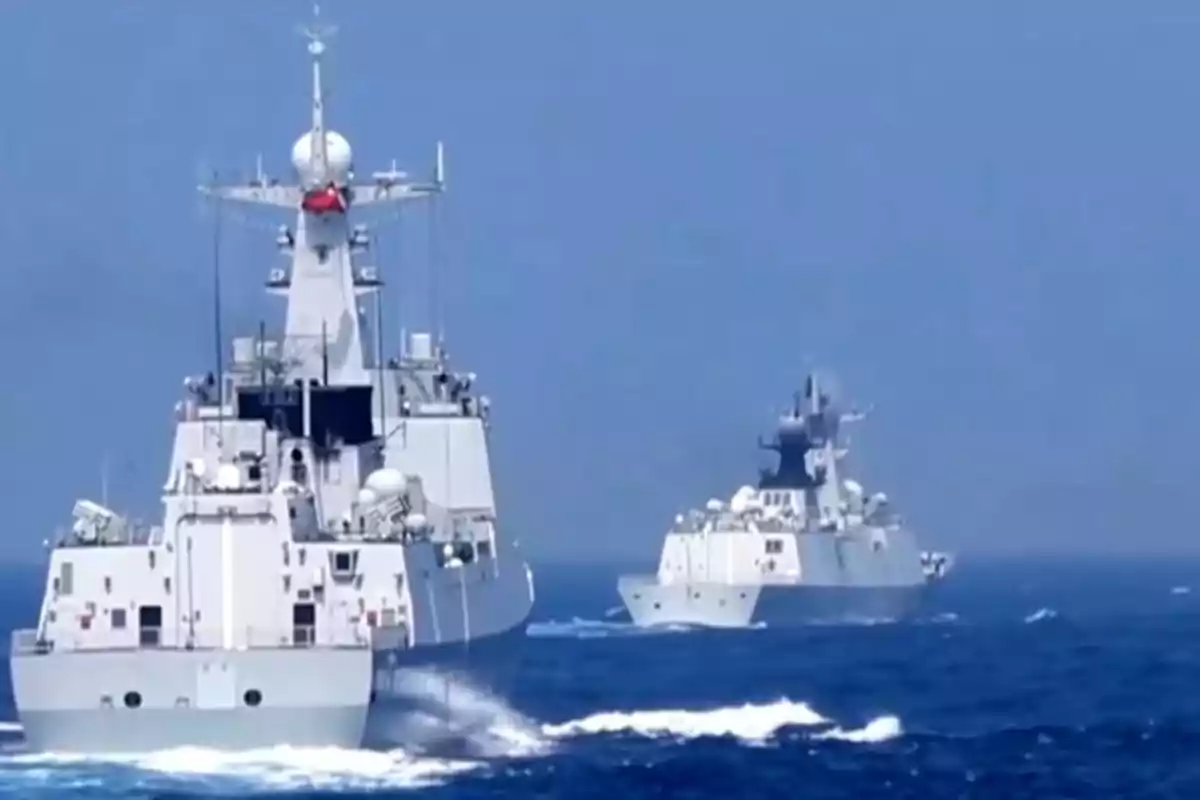 Dos buques de guerra navegando en el océano bajo un cielo despejado.