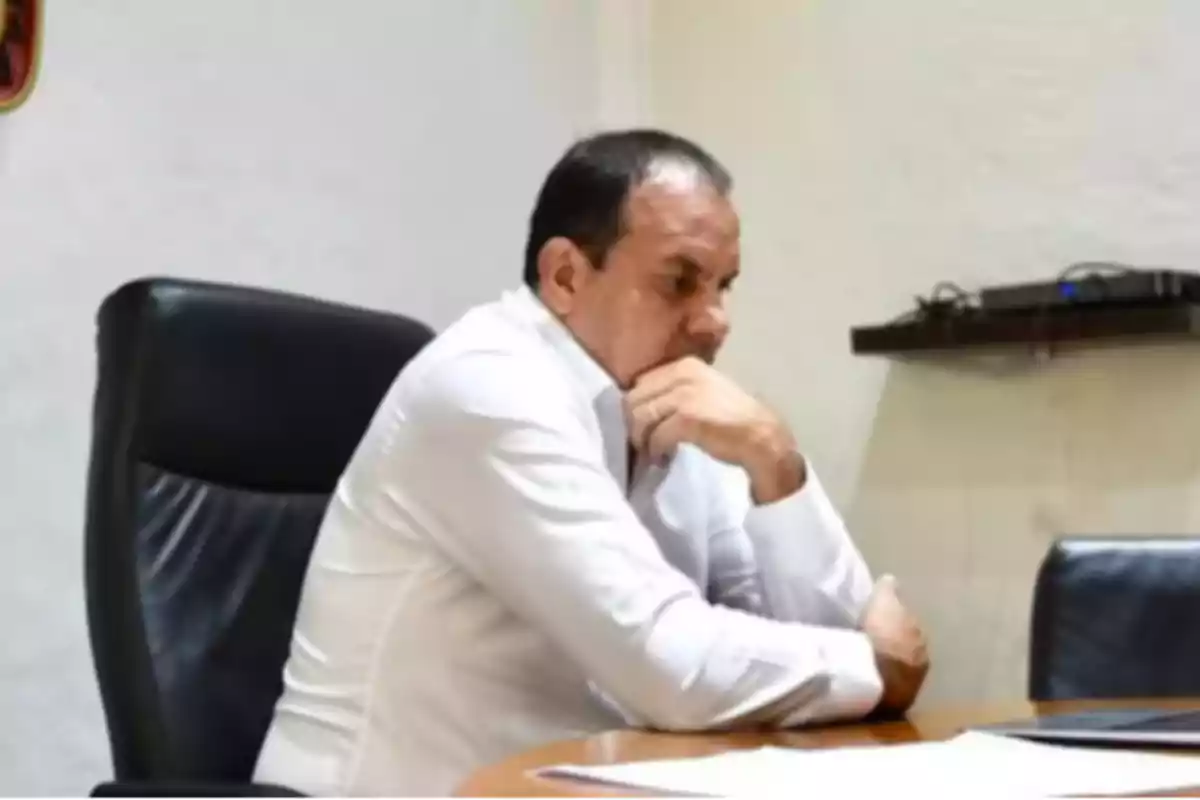 Man sitting in an office with a pensive expression.