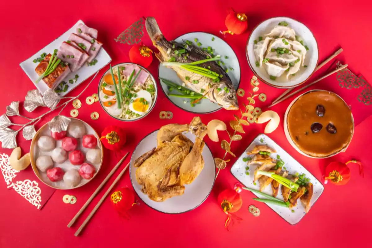 Una variedad de platos tradicionales asiáticos dispuestos sobre una mesa roja decorada con elementos festivos del año nuevo chino 2025.