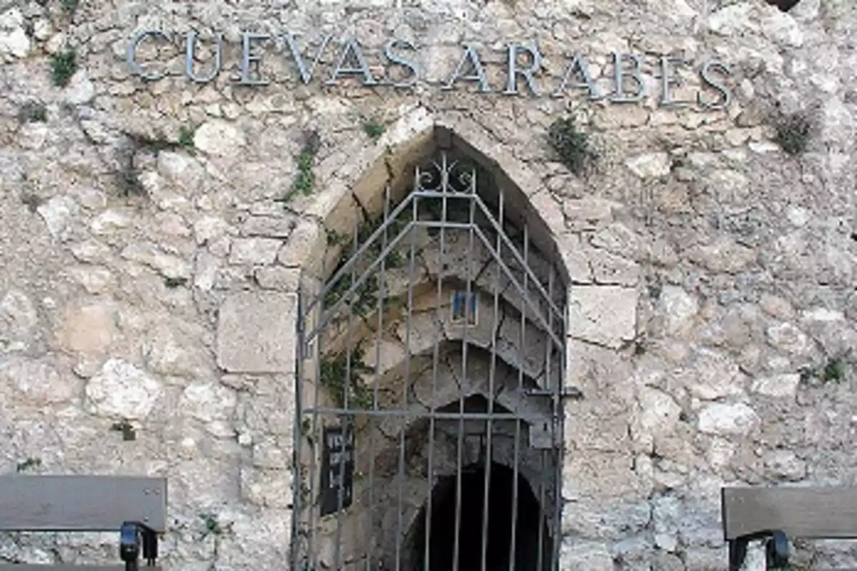 Entrada a las Cuevas Árabes con una puerta de hierro en una pared de piedra.