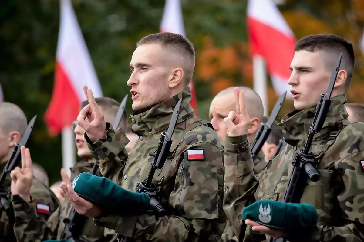 Soldados en uniforme camuflado realizan un juramento con banderas de fondo.