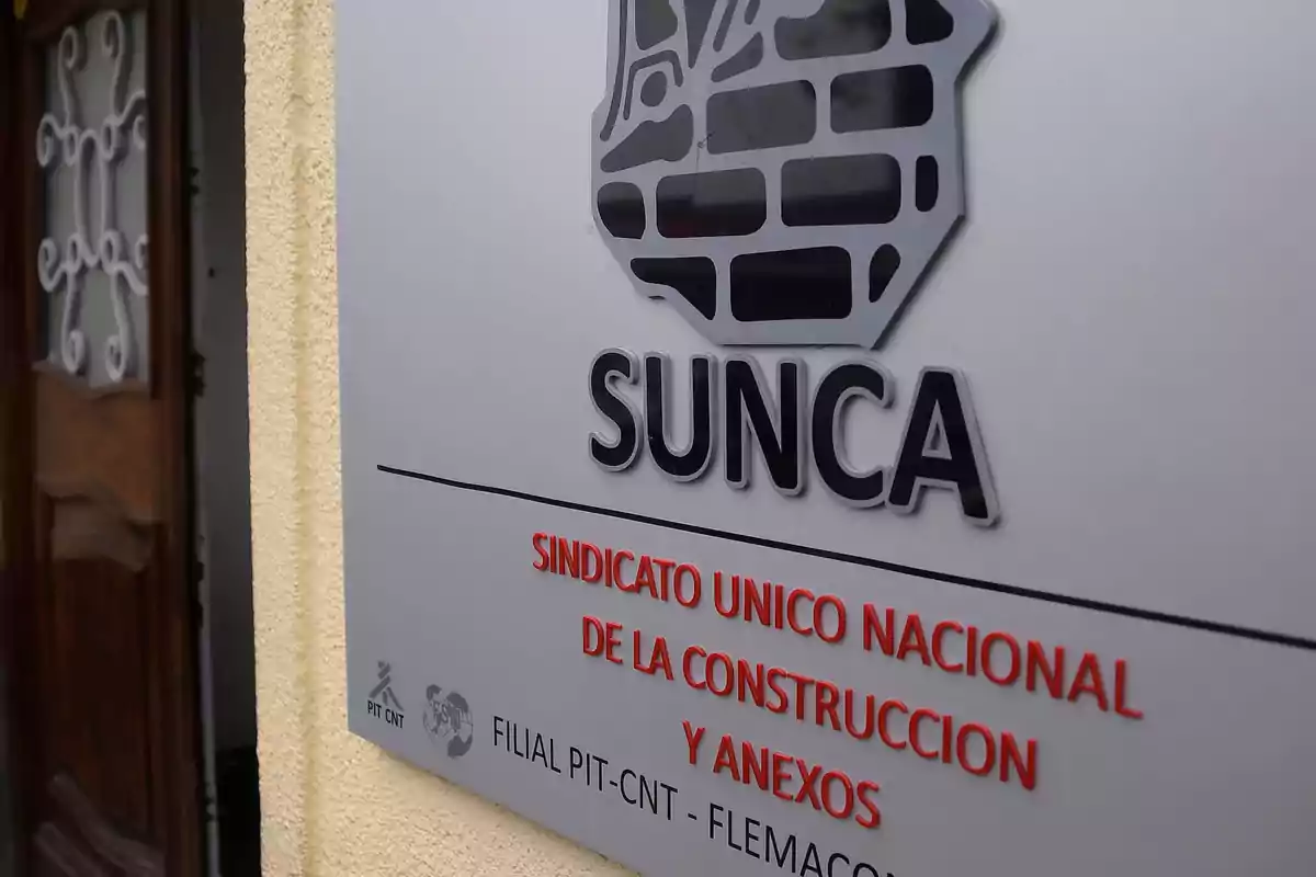 Placa del Sindicato Único Nacional de la Construcción y Anexos (SUNCA) en una pared junto a una puerta de madera.