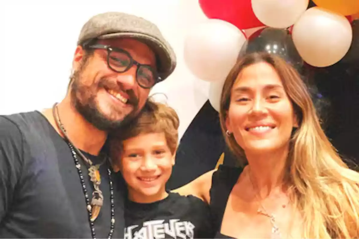 Una familia sonriente posando frente a un fondo de globos de colores.