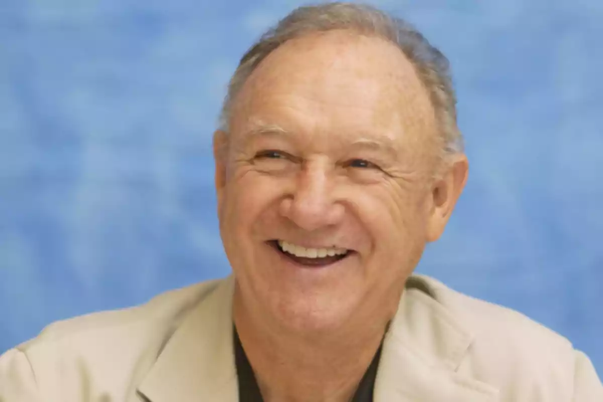 An elderly man smiling with a blue background.