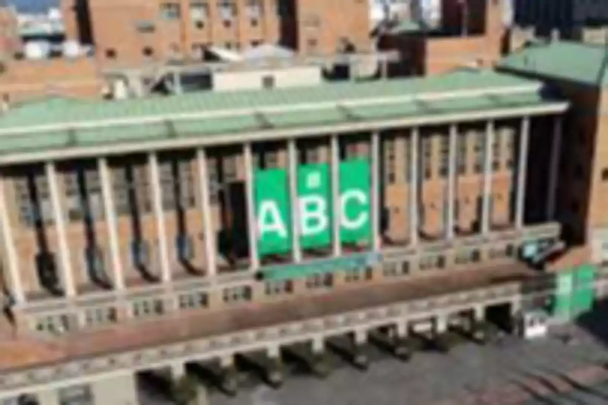 Edificio de ladrillo con columnas y un cartel verde con las letras 