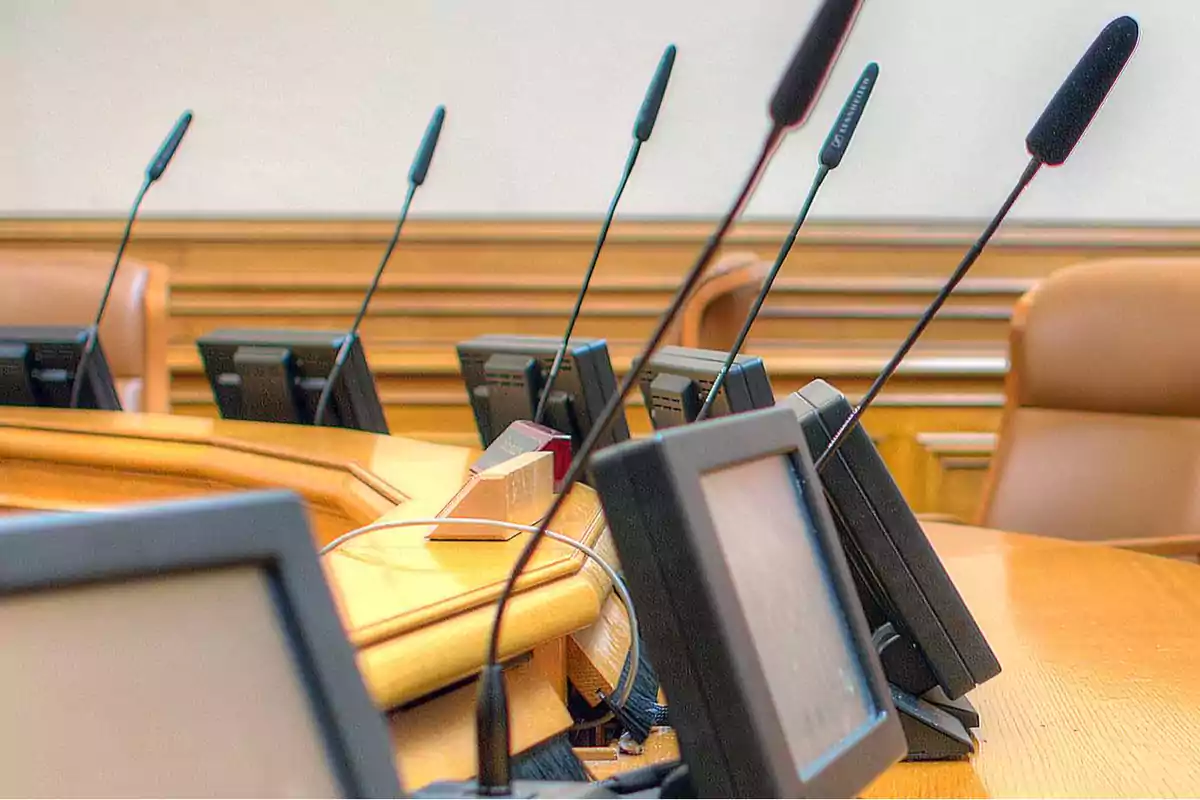 Micrófonos y pantallas en una sala de conferencias.