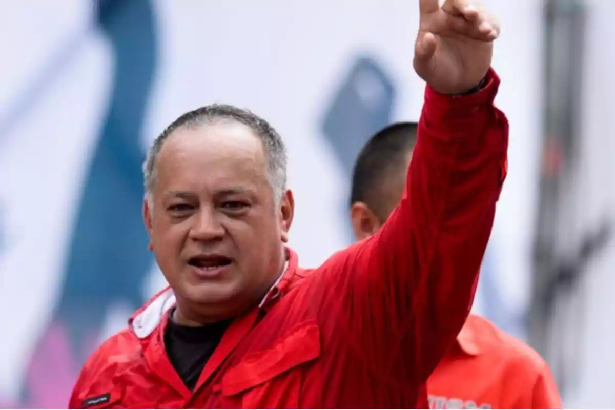 Un hombre con camisa roja levanta el brazo en un gesto enfático.