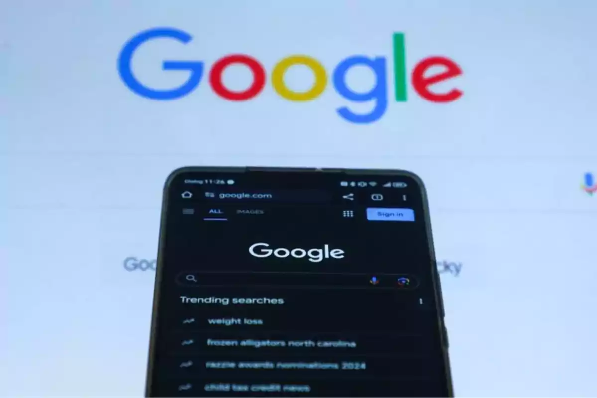 Teléfono móvil mostrando la página de inicio de Google con el logotipo de Google en el fondo.