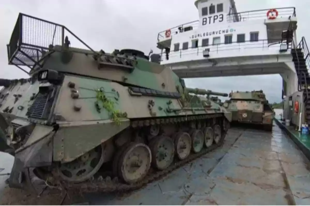 Tanques militares sobre un ferry en un entorno nublado.