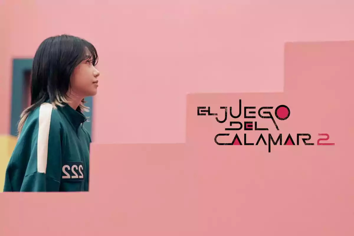 Una persona con chaqueta verde y el número 222 en un entorno de paredes rosadas con el texto "El Juego del Calamar 2".