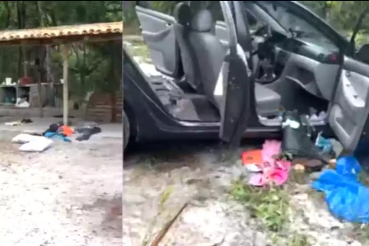 Un coche con las puertas abiertas y varios objetos esparcidos en el suelo cerca de una estructura techada en un entorno natural.