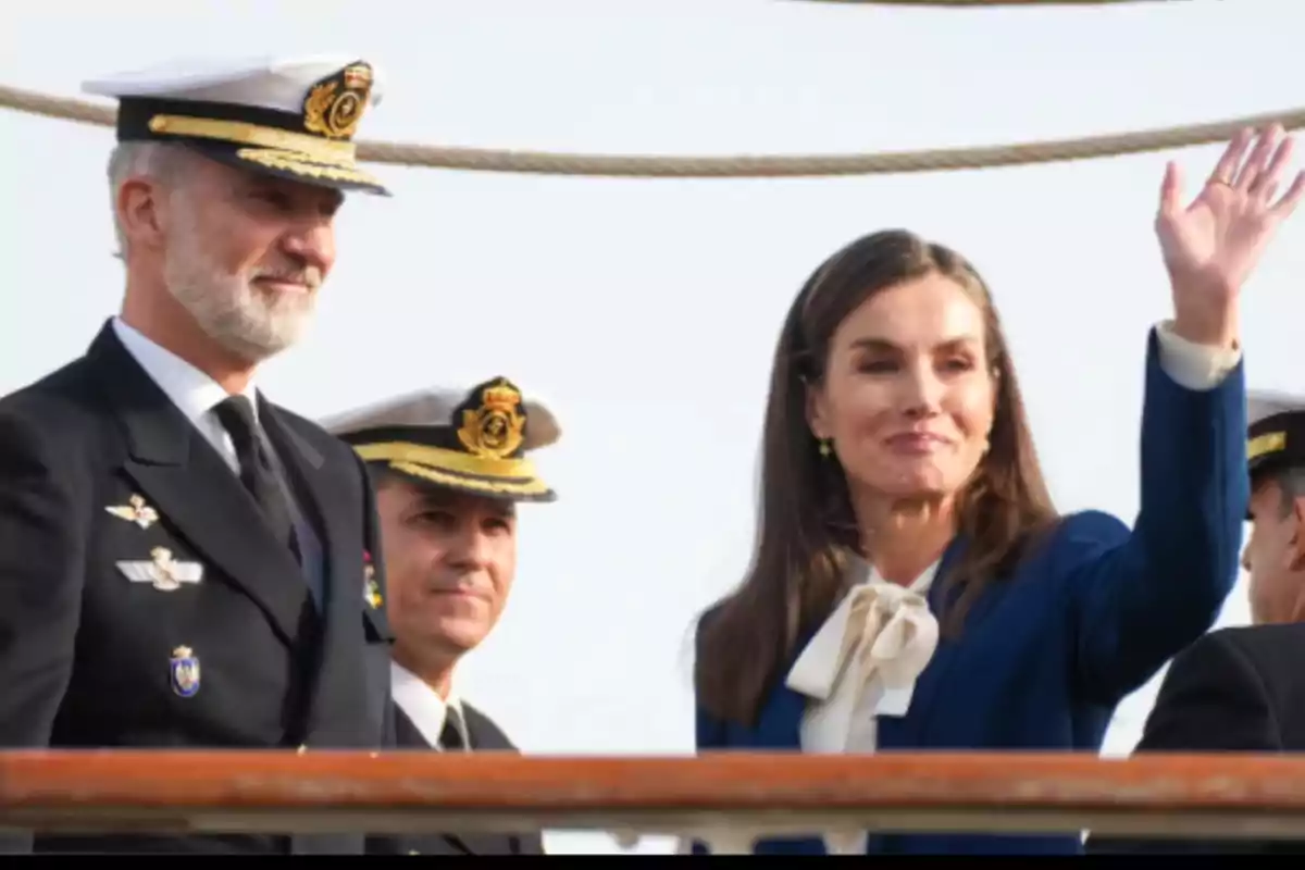 Personas en uniforme naval y una mujer saludando en un barco.