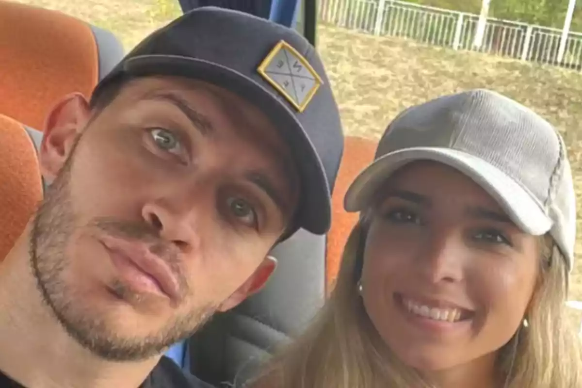 Two people with caps posing for a selfie in a vehicle.