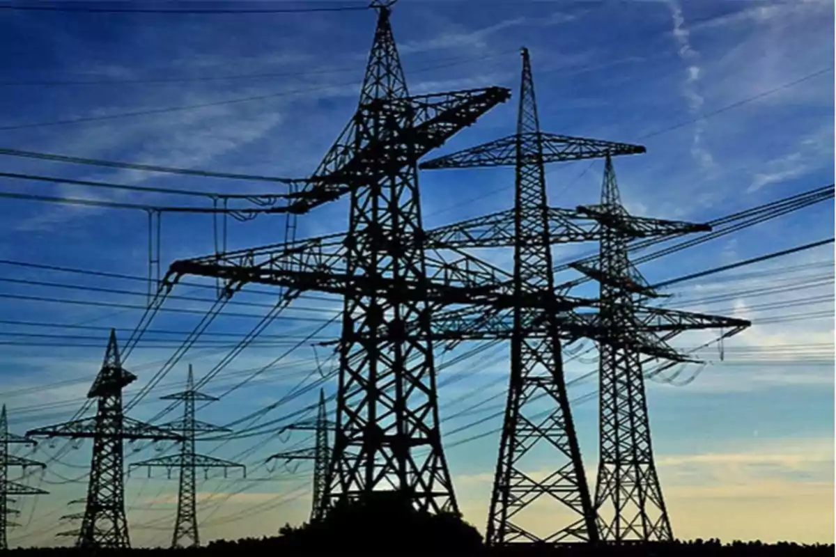 Torres de alta tensión con cables eléctricos en un paisaje al atardecer.