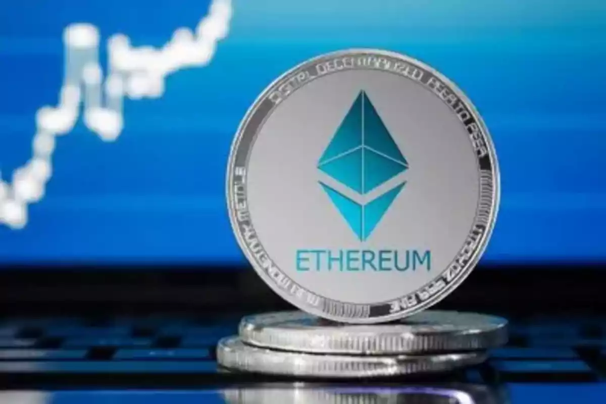 Moneda de Ethereum frente a una pantalla con gráfico financiero.