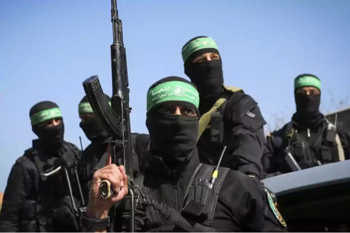 A group of masked people dressed in black with green bandanas on their heads holding weapons.