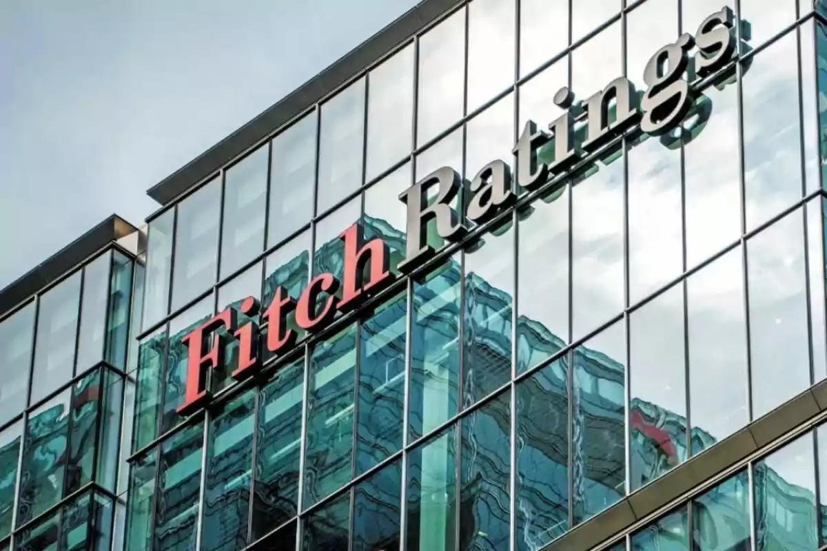 Edificio con fachada de vidrio que muestra el logo de Fitch Ratings reflejado en las ventanas.