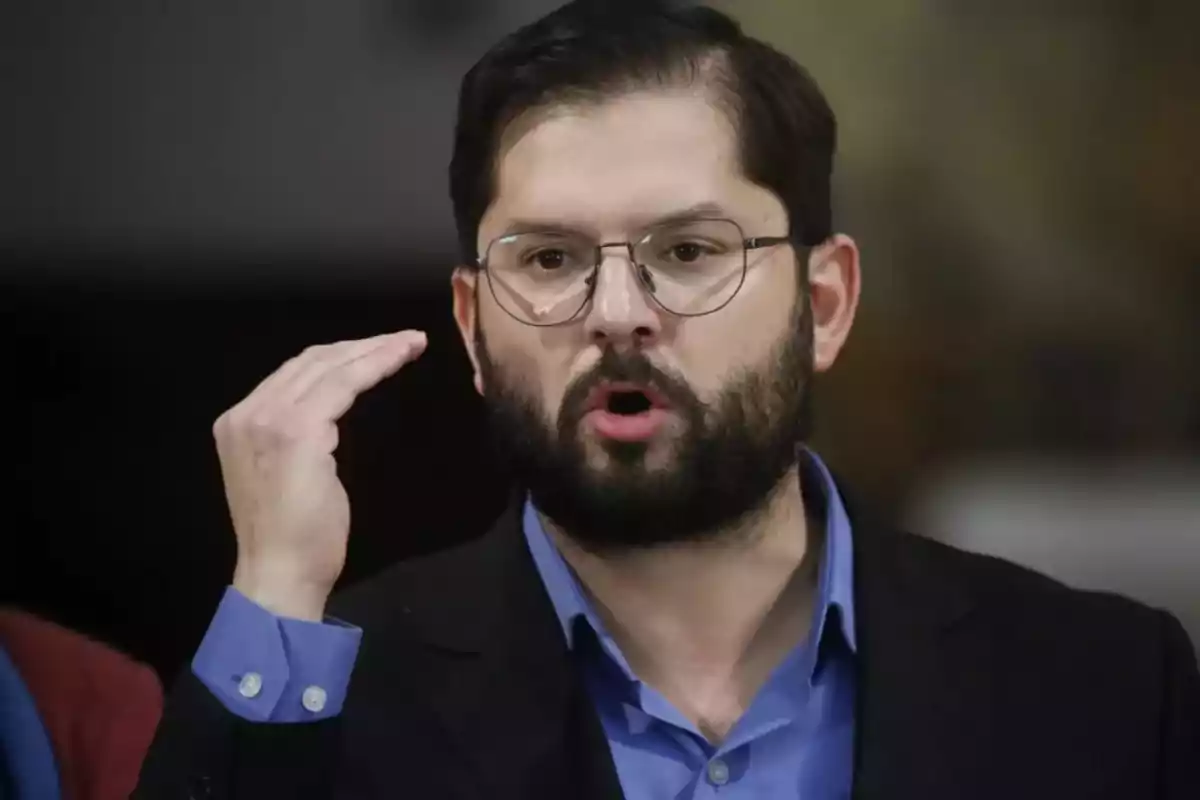 Un hombre con barba y gafas está hablando y gesticulando con la mano.