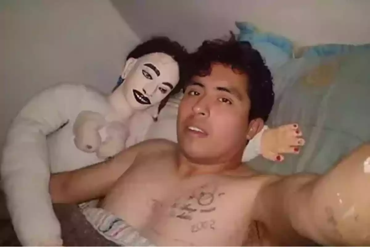 Un hombre acostado en la cama junto a una muñeca de trapo.