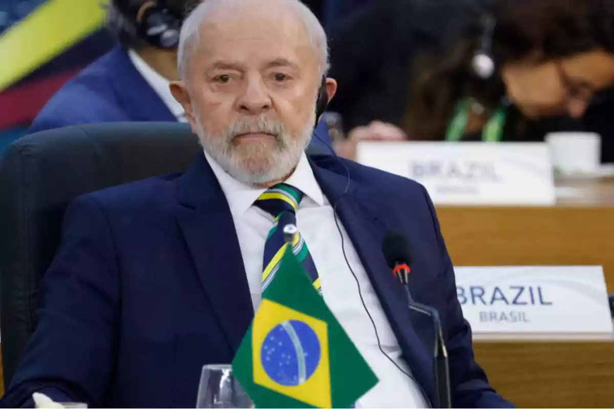 Hombre con traje y corbata en una conferencia internacional con una bandera de Brasil en primer plano.