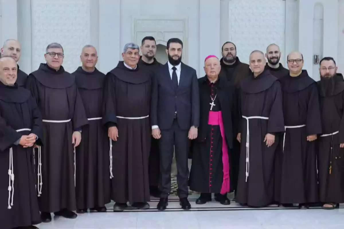 Un grupo de hombres con vestimenta religiosa y un hombre con traje posan juntos en un interior.