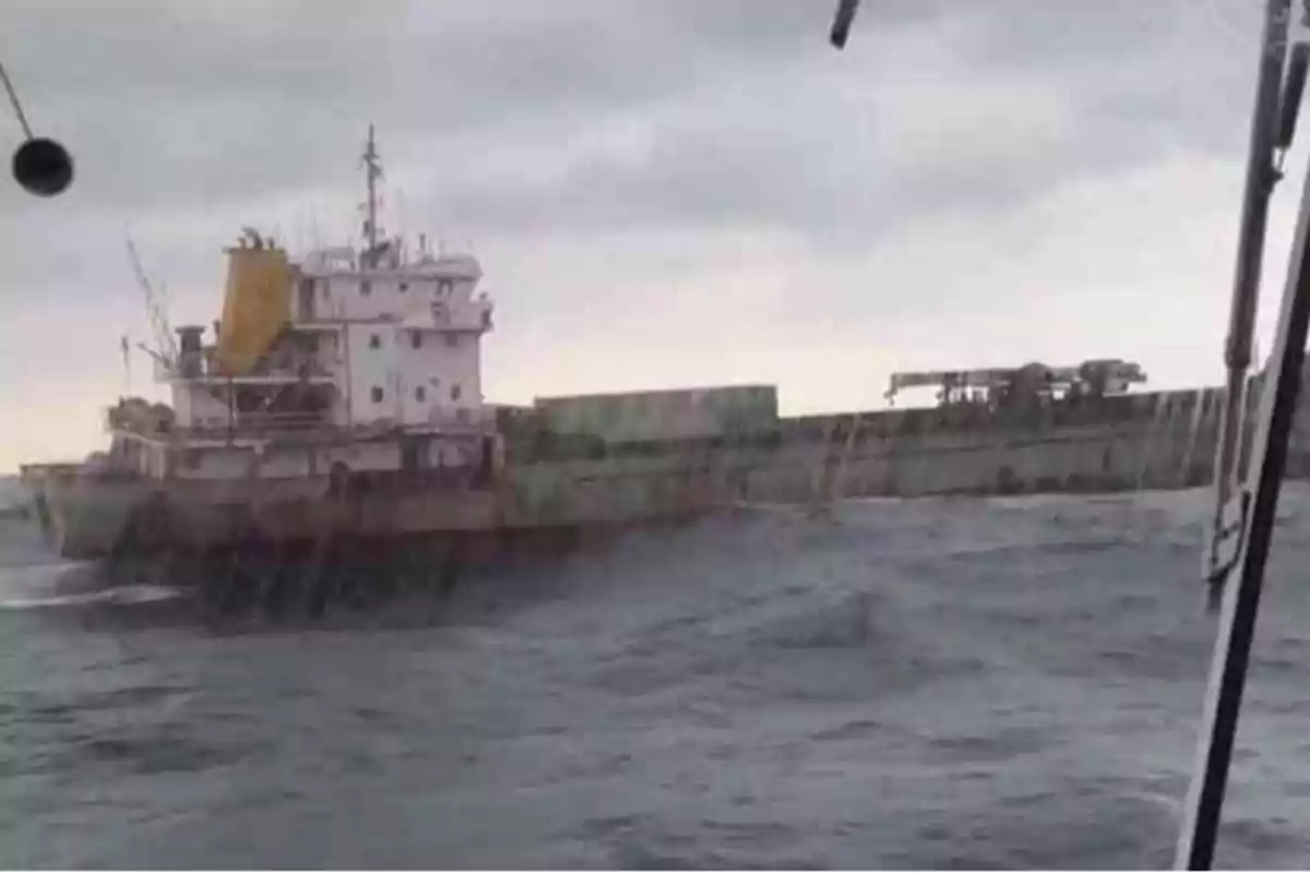 Un barco de carga navegando en un mar agitado bajo un cielo nublado.