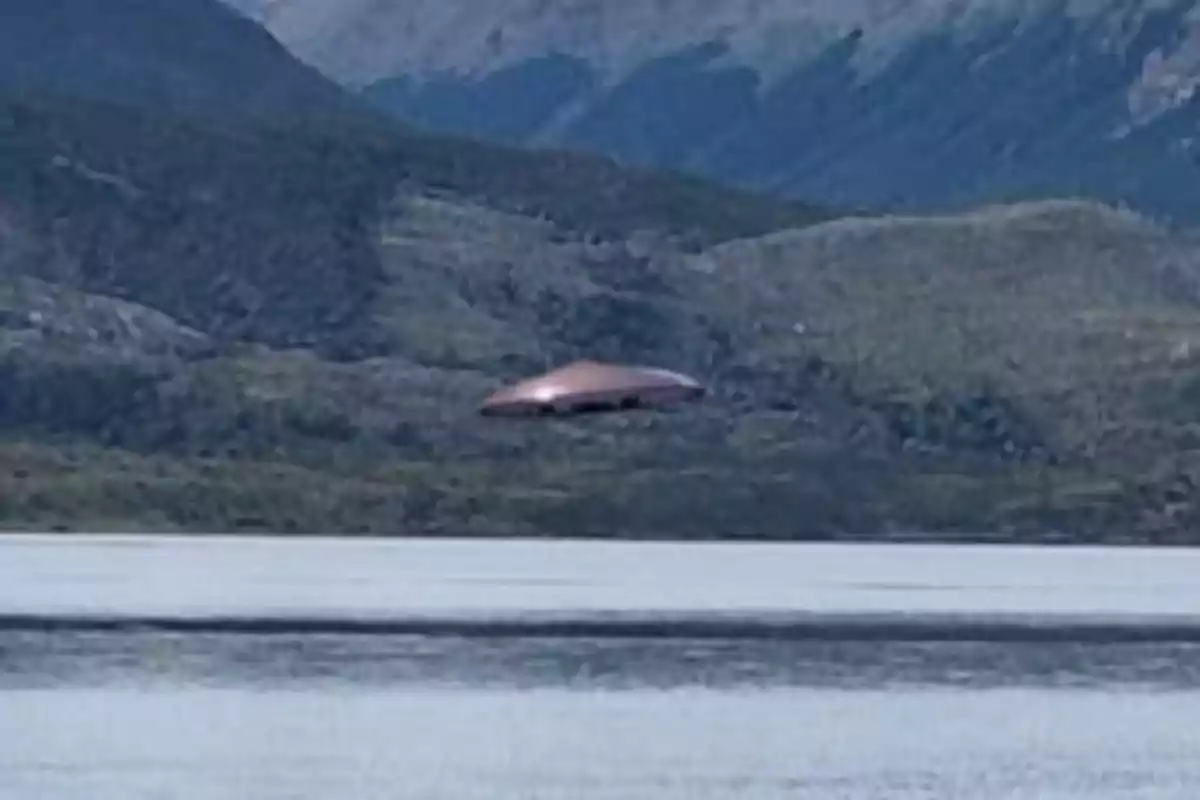 Un objeto volador no identificado sobre un paisaje montañoso y un lago.