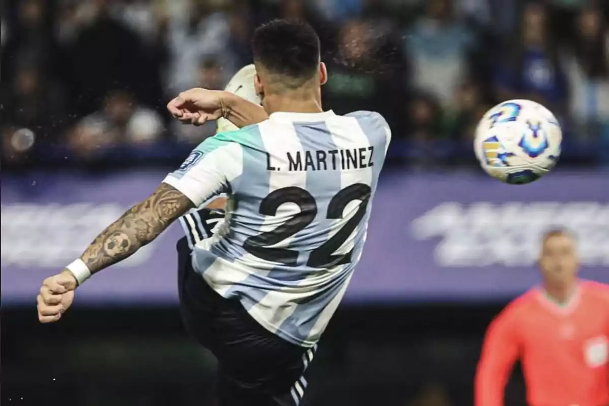 Jugador de fútbol con la camiseta de Argentina número 22 pateando un balón durante un partido.