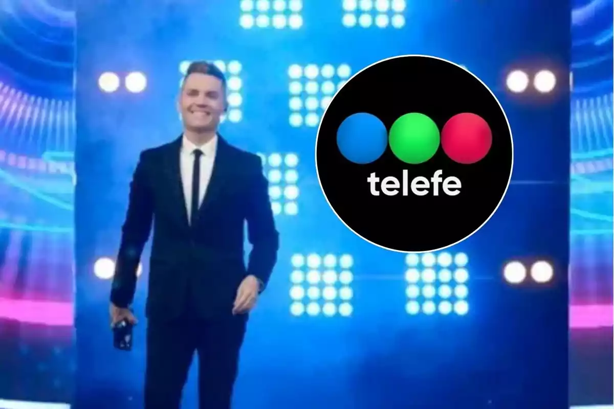 Un presentador de televisión sonríe en un escenario iluminado con luces azules y de fondo se ve el logotipo de Telefe.