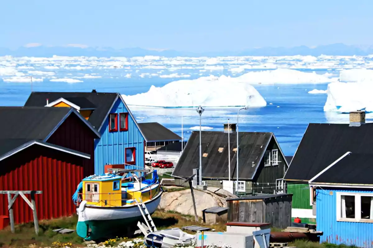 Casas coloridas junto al mar con icebergs en el fondo en un paisaje ártico.