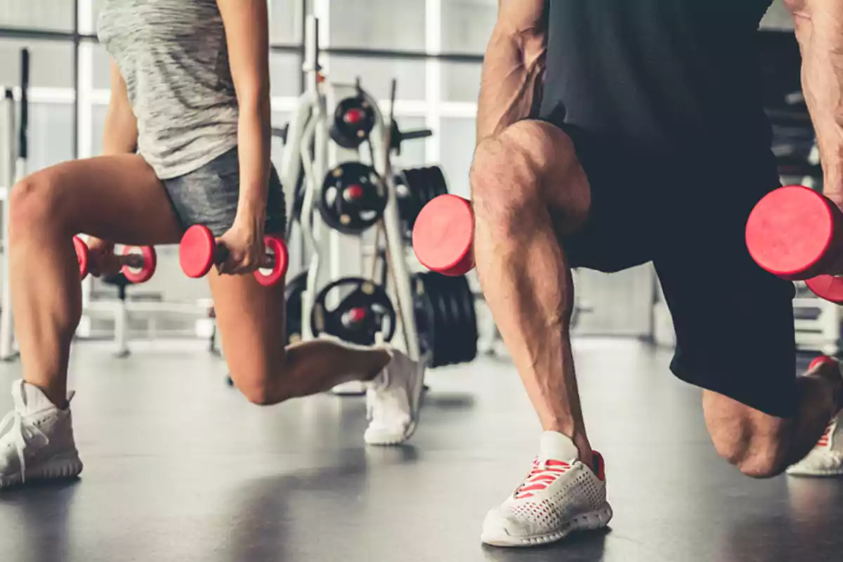 Dos personas haciendo ejercicio con mancuernas en un gimnasio.