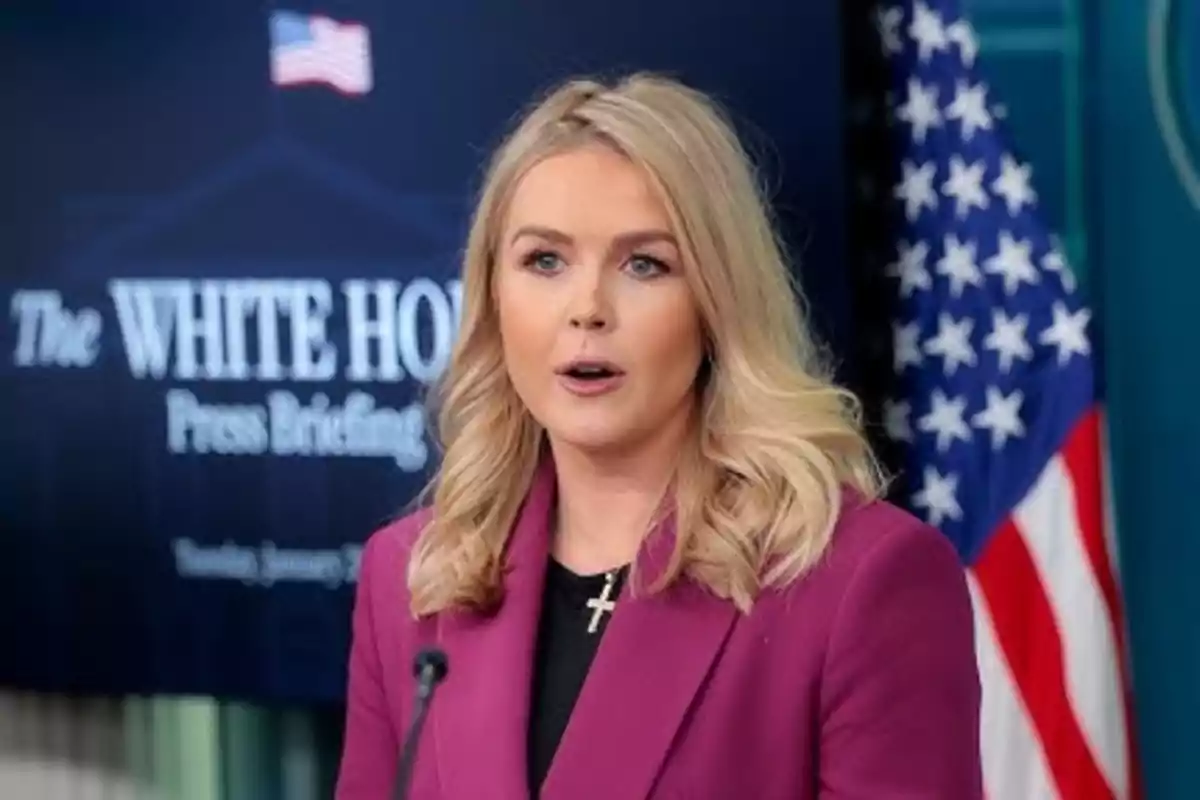 Mujer hablando en una conferencia de prensa en la Casa Blanca con una bandera de Estados Unidos al fondo.