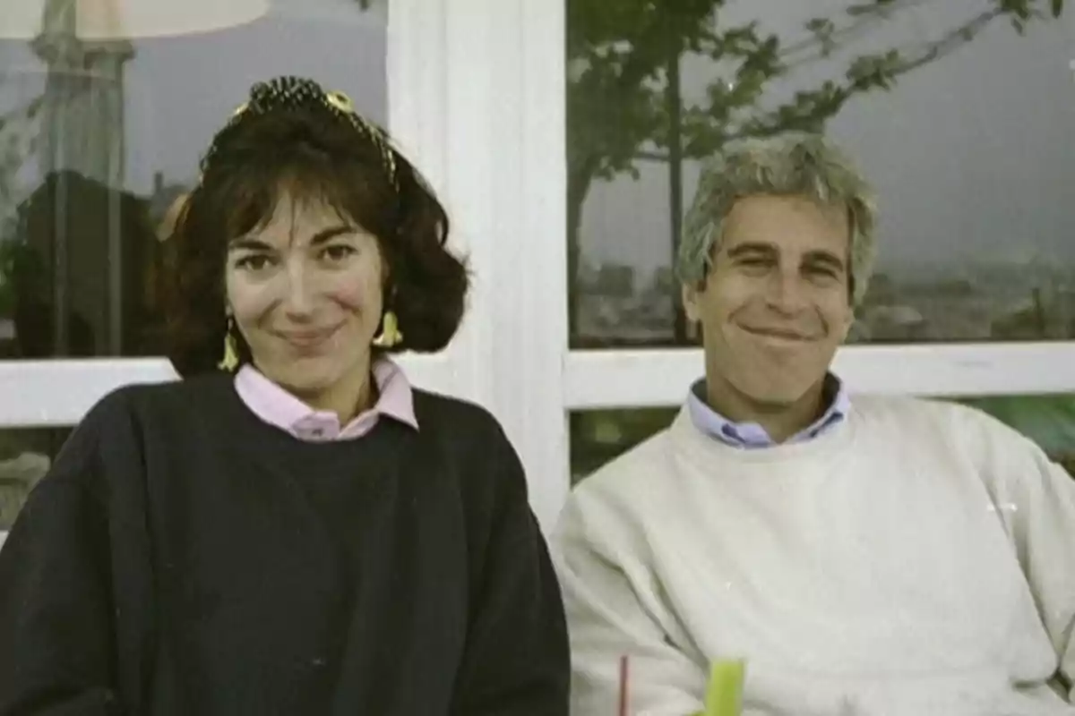 Dos personas sentadas juntas sonriendo frente a una ventana.