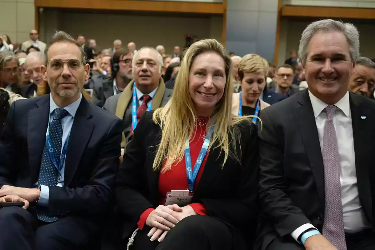 Un grupo de personas sentadas en una conferencia, con algunos de ellos sonriendo a la cámara.