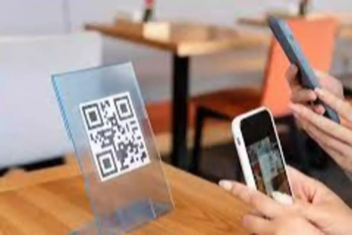 Personas escaneando un código QR en un restaurante con sus teléfonos móviles.