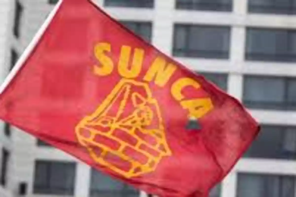 Red flag with the SUNCA logo and text waving in front of a building.