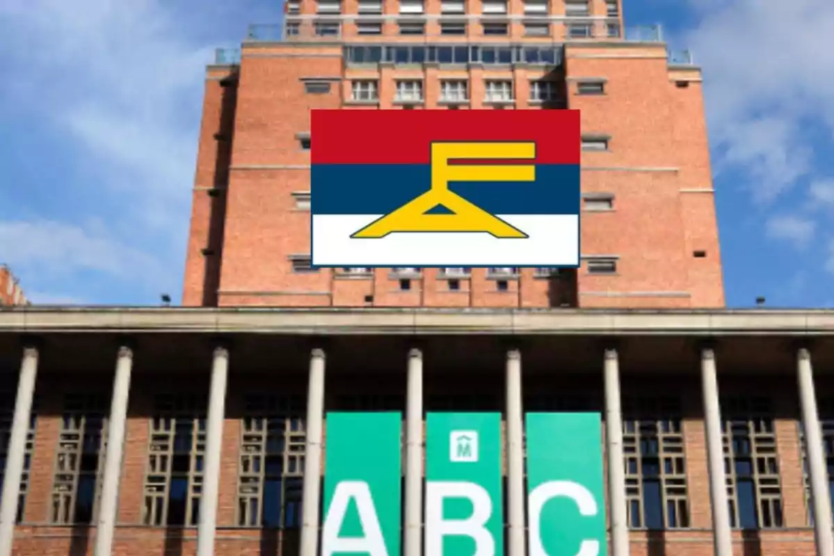 Edificio de ladrillo con columnas y un cartel verde con las letras ABC, sobre el cual se superpone una bandera con franjas roja, azul y blanca y un símbolo amarillo.