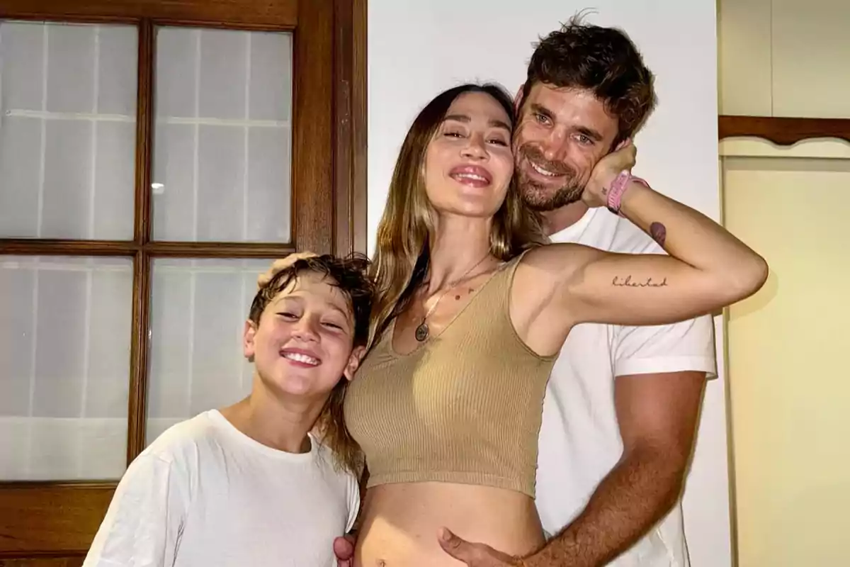 Una familia sonriente posando juntos frente a una puerta de madera.