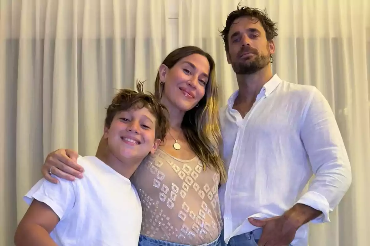 Una familia posando juntos frente a una cortina blanca.