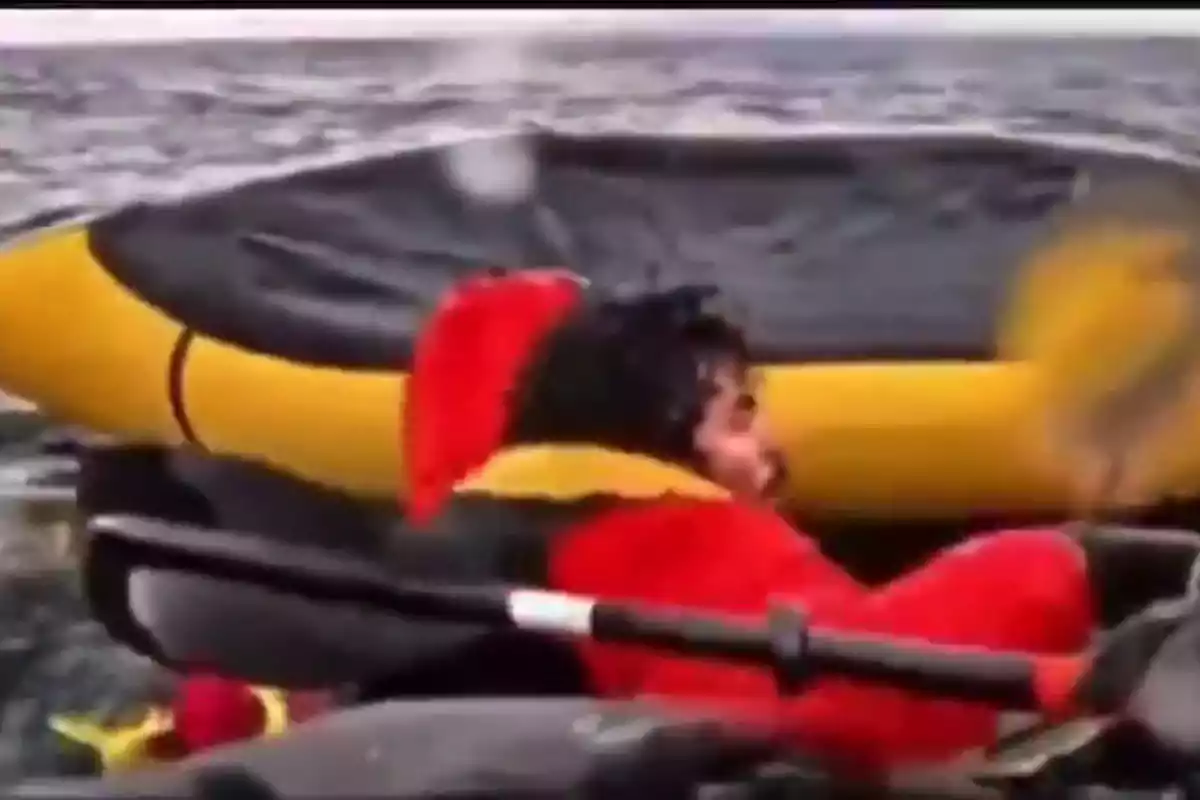 Persona con chaqueta roja y amarilla en un bote inflable en el agua.