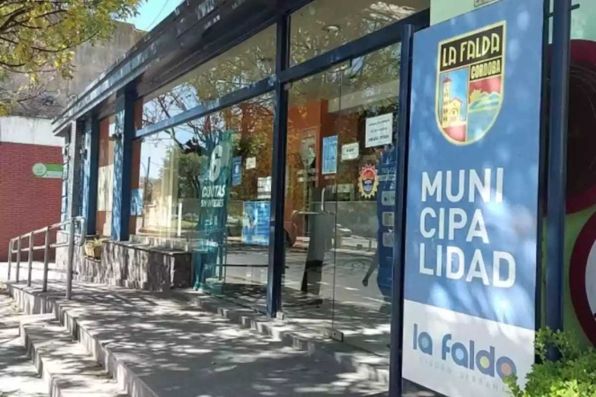 Edificio de la municipalidad de La Falda, Córdoba, con un cartel azul y un escudo en la entrada.