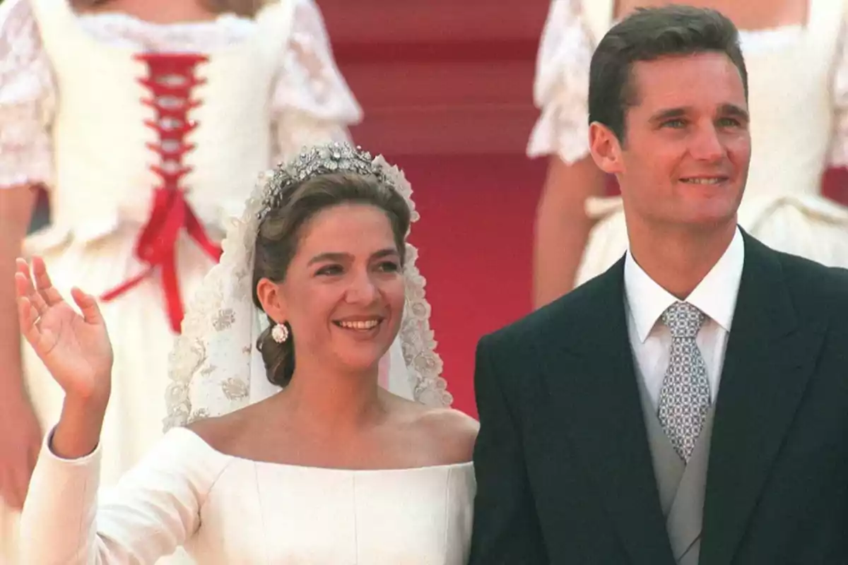 Una pareja sonriente en su boda con la novia vestida de blanco y el novio con traje oscuro.